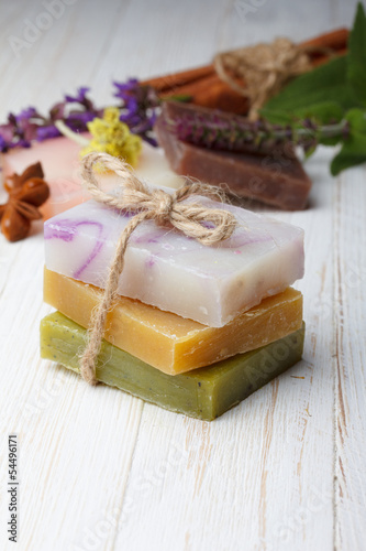 Different natural homemade soap on wooden table with herbs