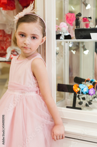 Beautiful girl in pink dress in shop of childrens bijouterie