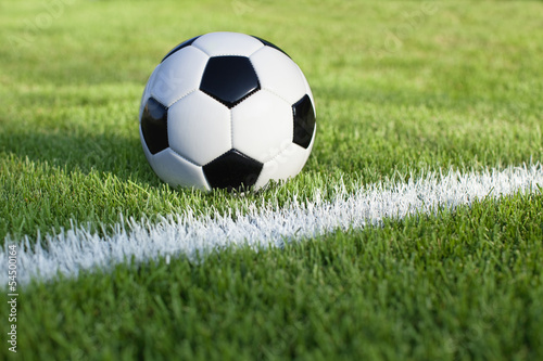 Soccer ball sits on grass field with white stripe