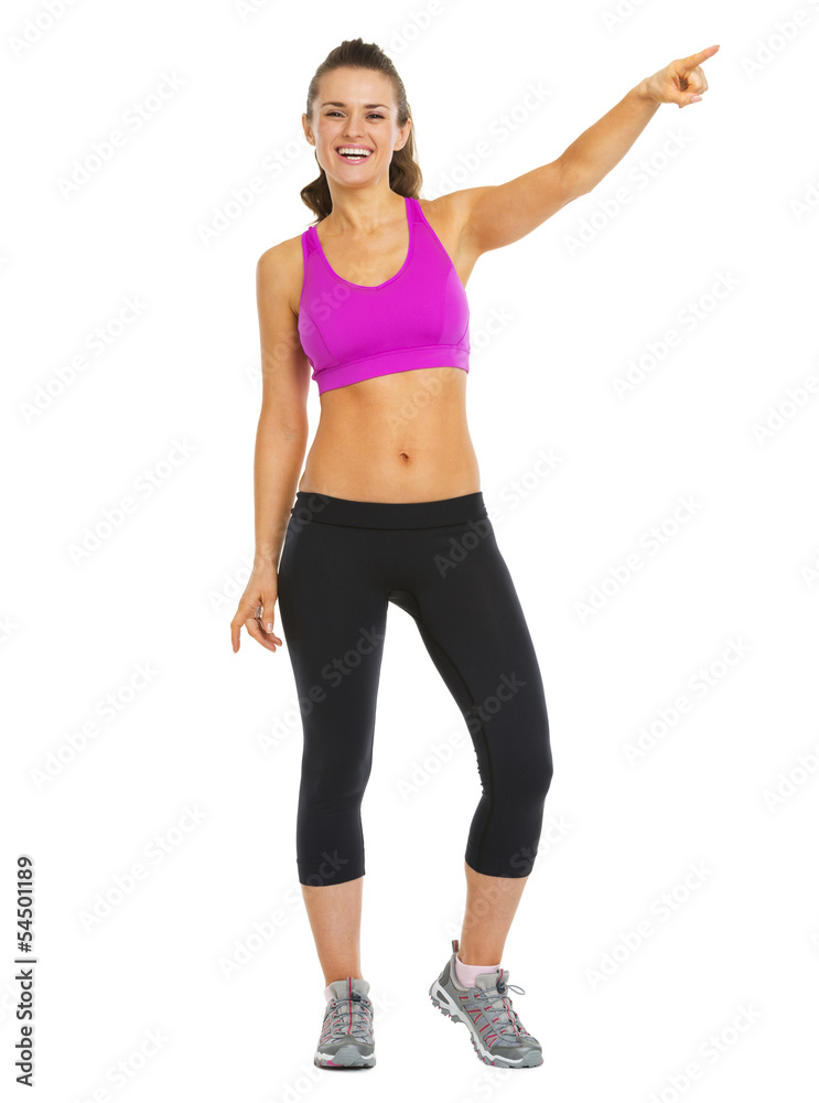 Smiling fitness young woman pointing on copy space Smiling fitness young woman pointing on copy space