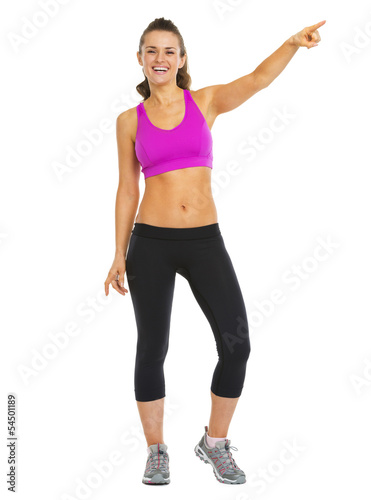 Smiling fitness young woman pointing on copy space