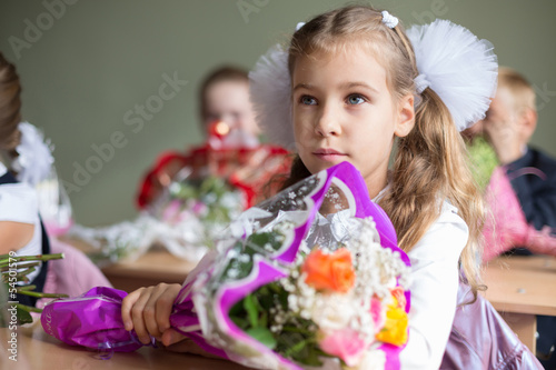 Portrait of beautiful girl sitting at desk with bouquet