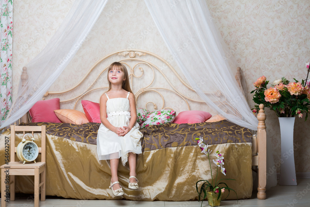 A smiling girl sitting on bed in bedroom decorated with flowers