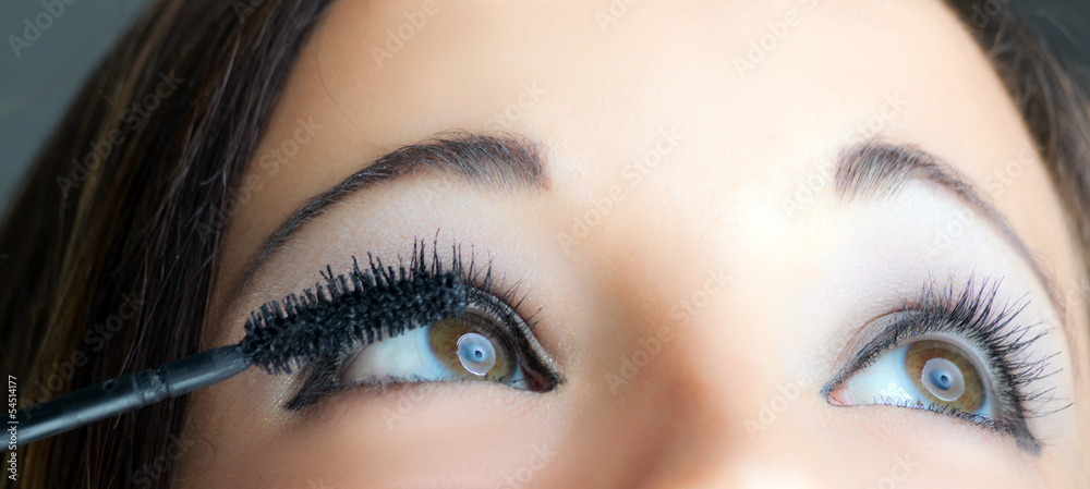 Portrait of a beautiful woman applying makeup