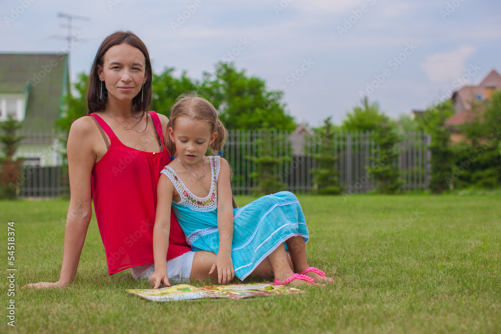 young mother and her cute daughter reading a book and enjoying young mother and her cute daughter reading a book and enjoying