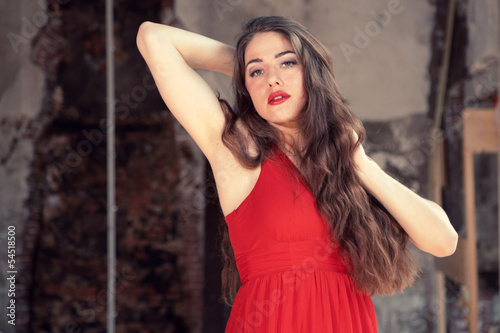 Sensual fashion woman wearing red dress posing in old urban buil