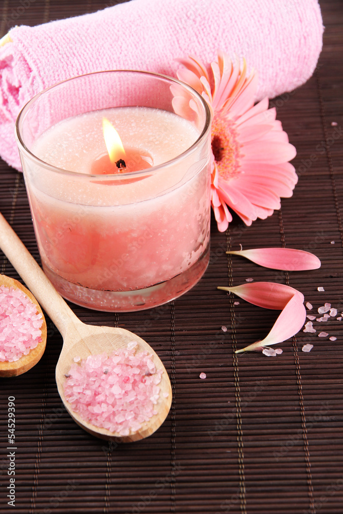Beautiful pink candle with flower and towel on bamboo mat Beautiful pink candle with flower and towel on bamboo mat