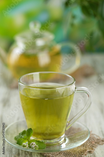 Cup of herbal tea with fresh mint flowers on wooden table