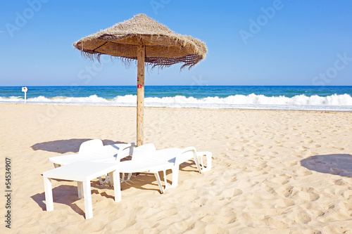 Thatched umbrella and beach chairs on the beach near Lagos Portu photo