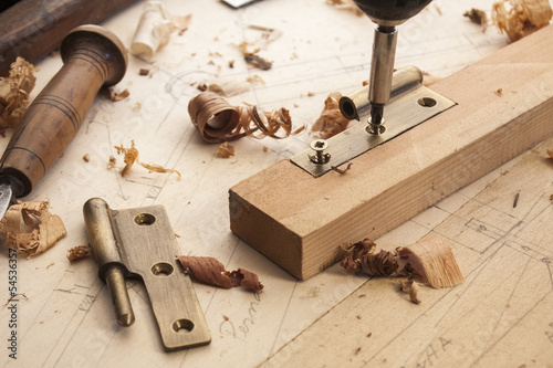 close up  of a carpenter screwed a hinge on a wooden plank