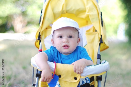 thoughtful baby boy age of 9 months on yellow baby carriage