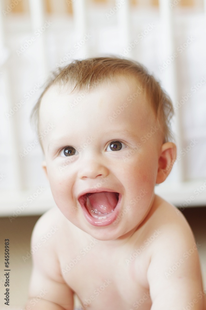 funny laughing baby against white bed