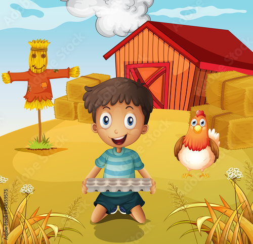 A boy holding an empty egg tray at the farm with a scarecrow photo