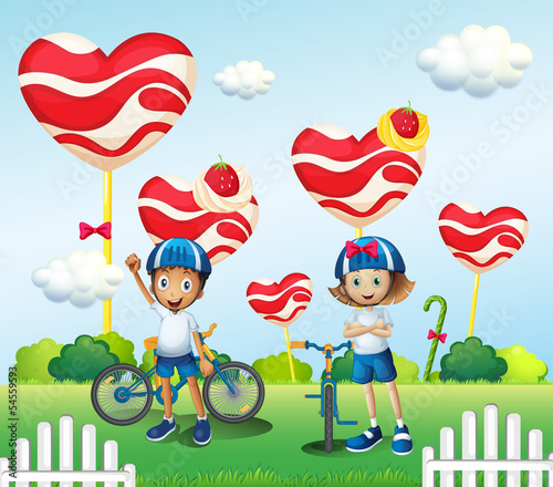 A boy and a girl biking near the giant lollipops