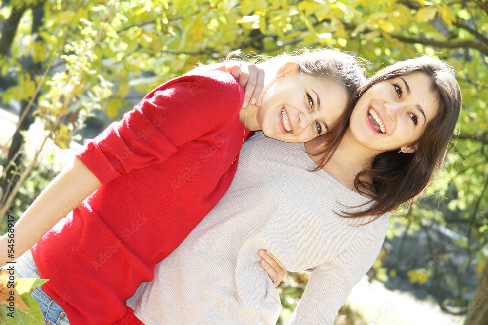 Fototapeta premium two young happy girls in autumn park outdoor portrait