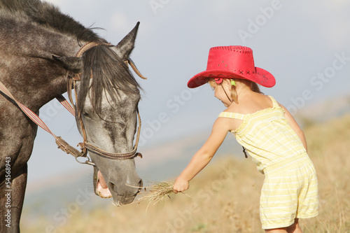 girl feeding a horse on farm outdoor portrait