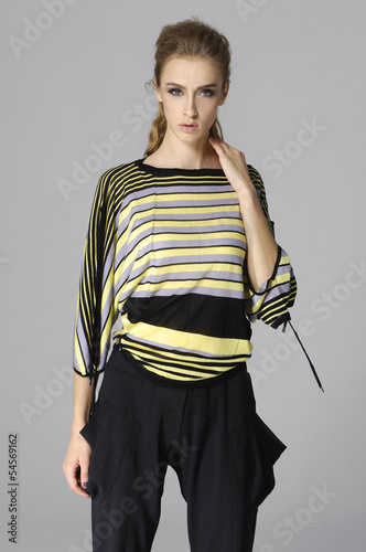 Beautiful casual young woman standing isolated against gray