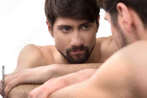 Mirror image. Young man looks at himself in the mirror