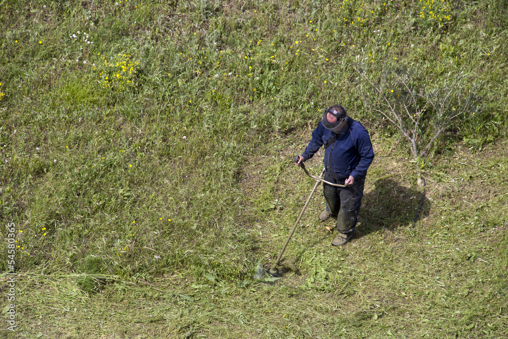 Adult man working with a lawn mower trimmer Adult man working with a lawn mower trimmer