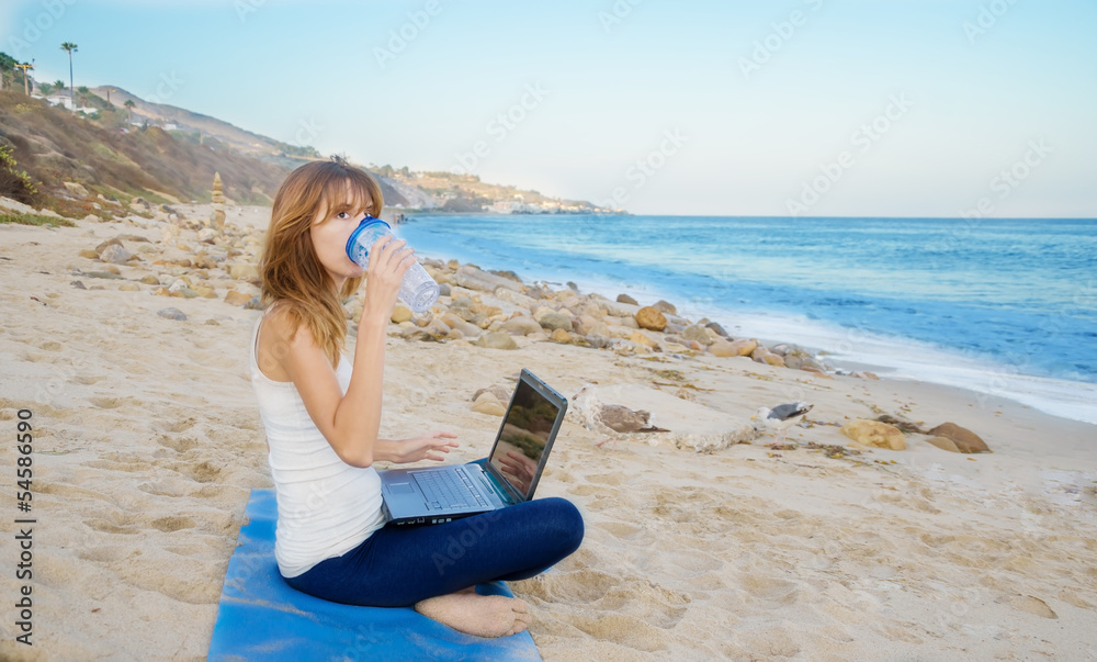 Yang woman with laptop by the ocean