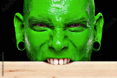 Foto Mann mit grünem Gesicht beißt in die Tischkante