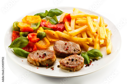 Grilled steaks  French fries and vegetables