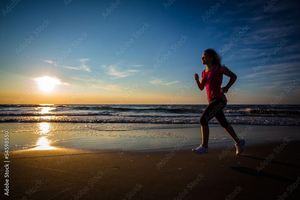 Teenage girl running, jumping on beach