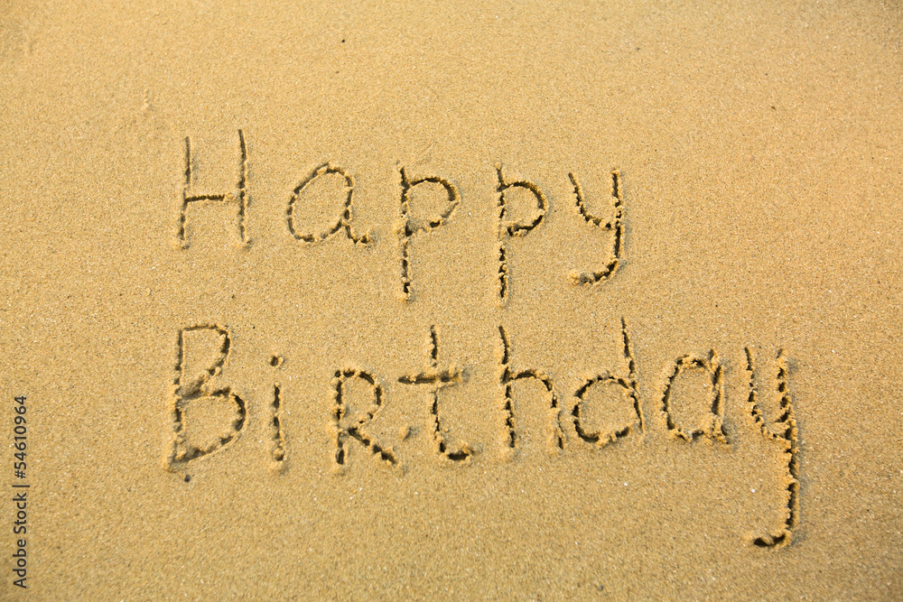 Fototapeta premium Inscription Happy Birthday on texture of wet sand.