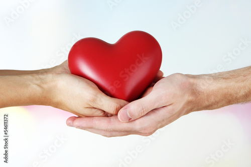 Heart in hands on light background