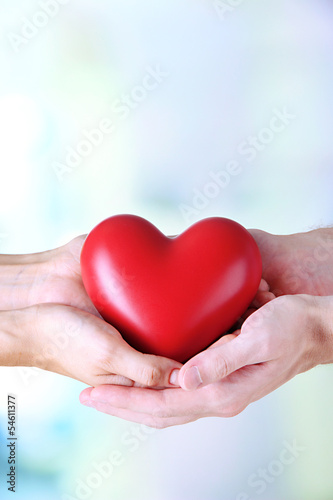 Heart in hands on light background