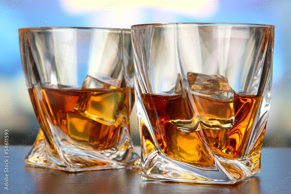 Glasses of whiskey, on bright background