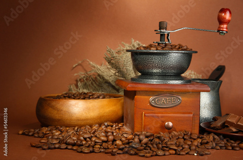 Coffee grinder, turk and coffee beans on brown background