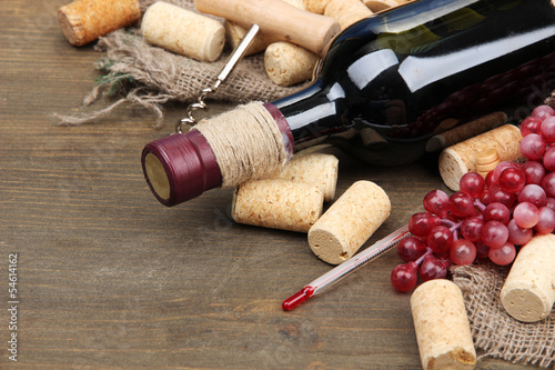 Bottle of wine, grapes and corks on wooden background