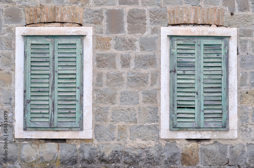 Two old windows with blue closed shutters on an old hous