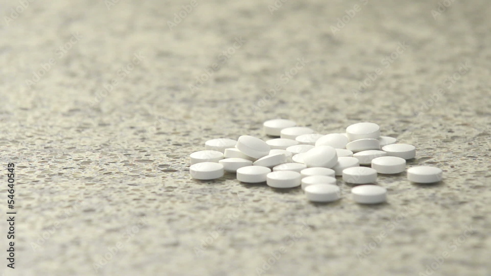 Hand dumps out pile of generic white pills, medicine Hand dumps out pile of generic white pills, medicine