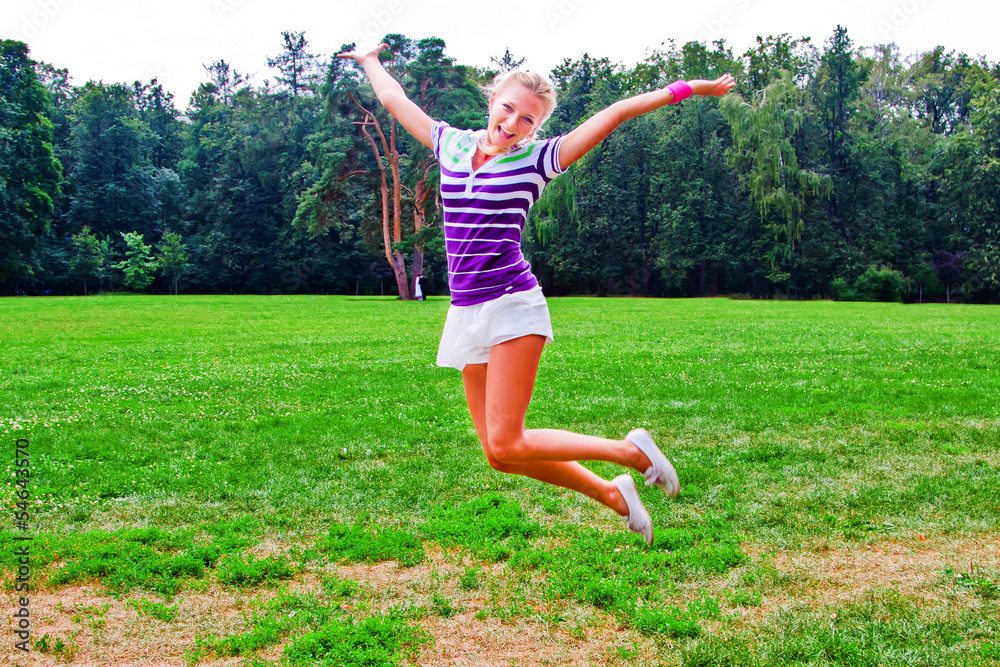 young and beautiful woman jumping on a summer lawn young and beautiful woman jumping on a summer lawn