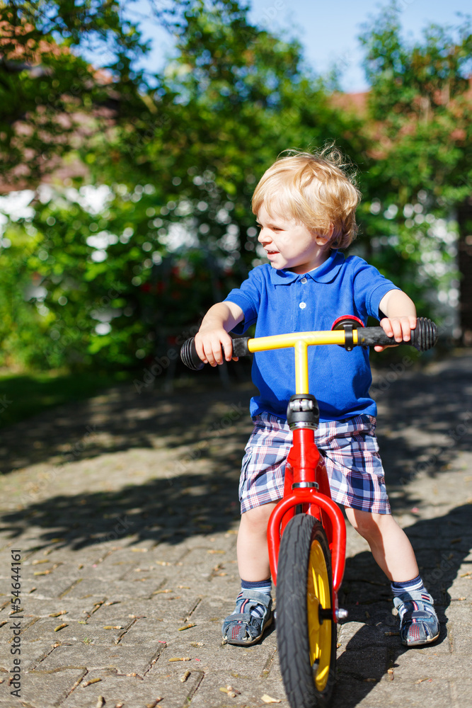 Little toddler boy riding on his bycicle in summer Little toddler boy riding on his bycicle in summer