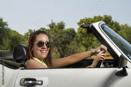 View of a beautiful woman posing on a white convertible car.