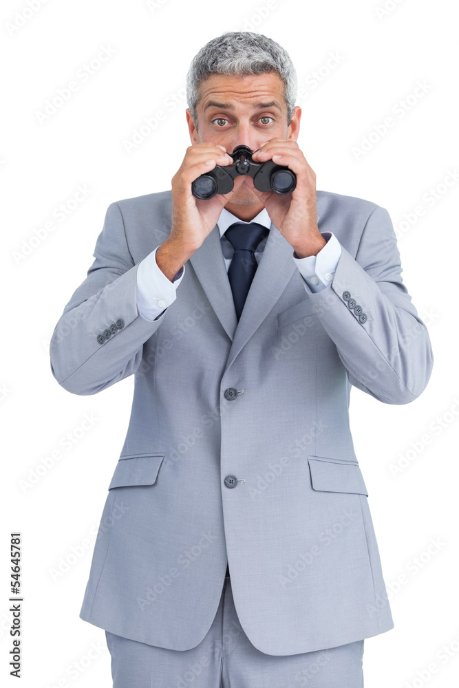 Curious businessman observing with binoculars Curious businessman observing with binoculars