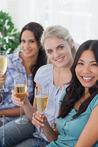 Happy friends enjoying white wine together looking at camera