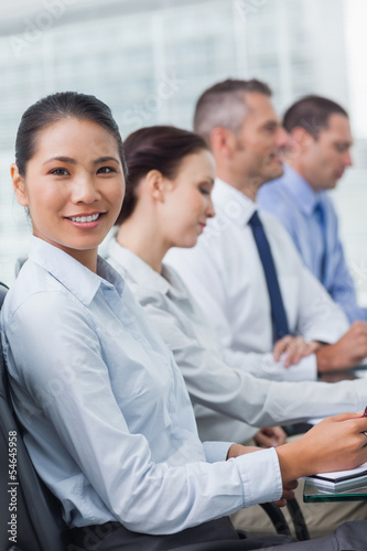 Cheerful employee attending presentation with her colleagues