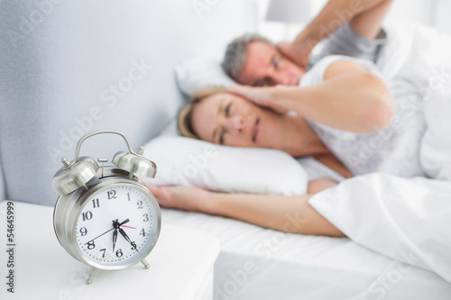Couple covering their ears from alarm clock noise