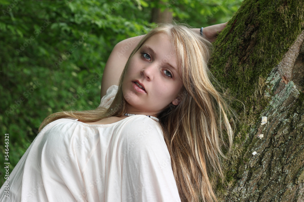 junge Frau lehnt am Baum
