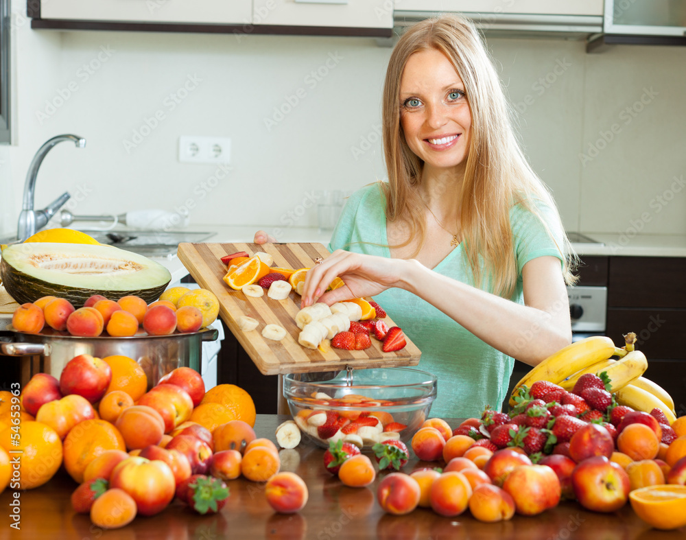 Happy blonde woman cooking with ripe fruits