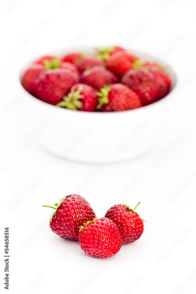 Pile of fresh strawberries in front of white bowl Pile of fresh strawberries in front of white bowl