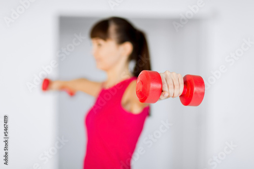 sporty woman hands with light red dumbbells