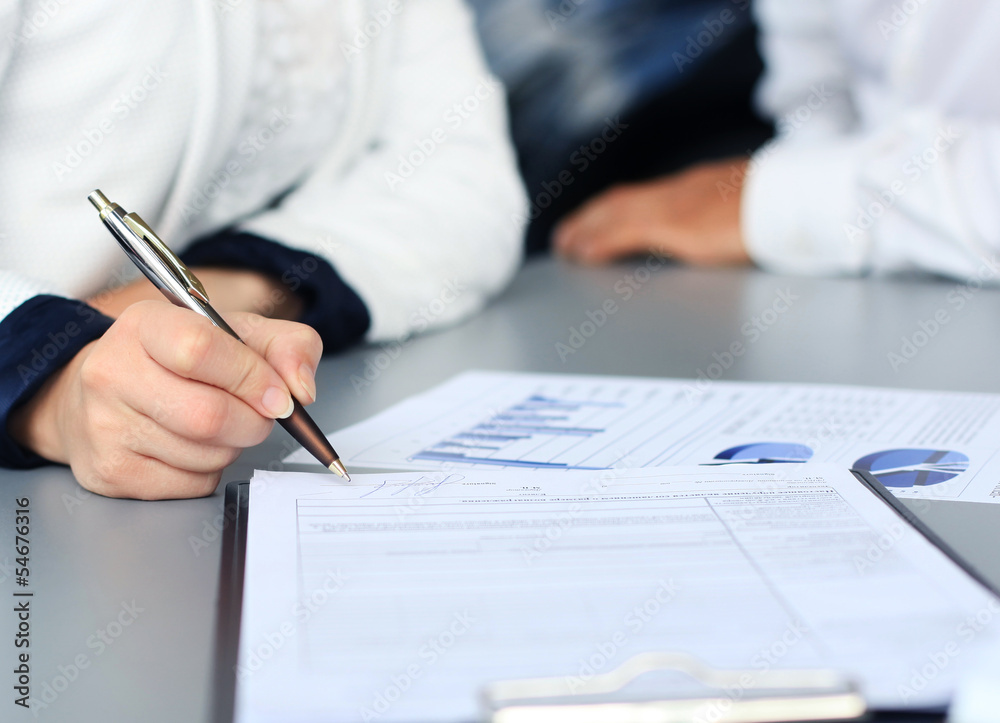 Businesswoman sitting at office desk signing a contract Businesswoman sitting at office desk signing a contract