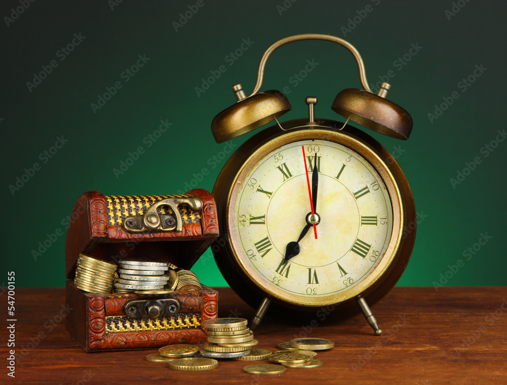Antique clock and coins on wooden table on dark color Antique clock and coins on wooden table on dark color
