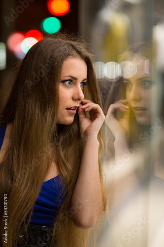 Girl looks at night shopwindow