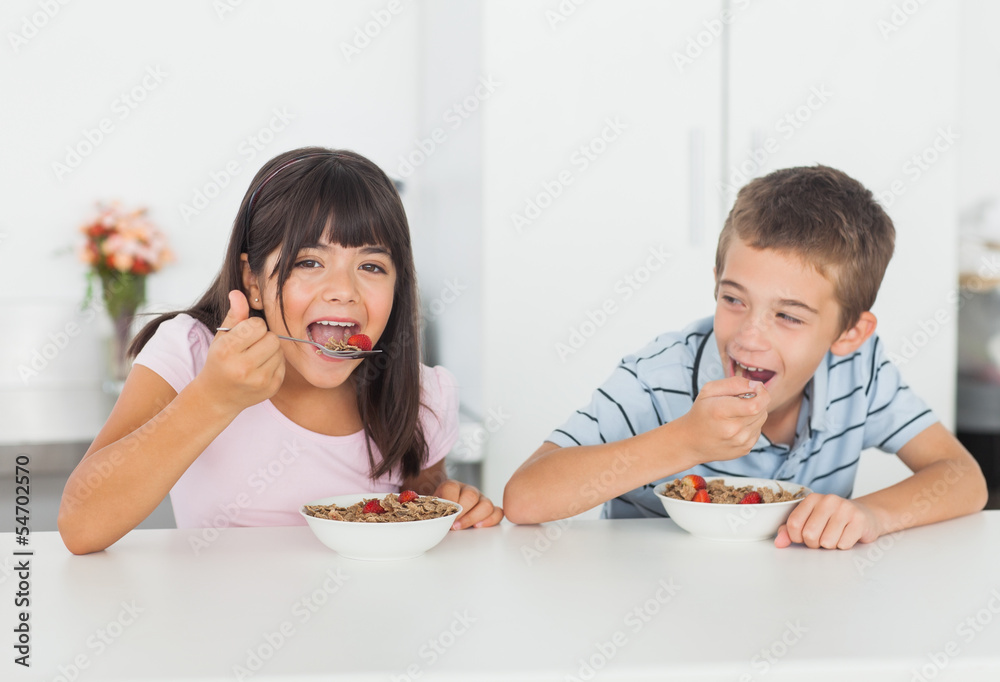 Siblings eating cereal for breakfast in kitchen Siblings eating cereal for breakfast in kitchen